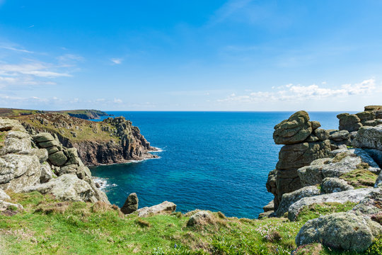 Grassy cliffs overlooking the sea on a partially sunny day in Land&rsquo;s End, UK.