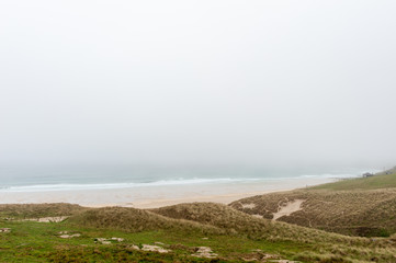 Fototapeta na wymiar Grassy hills over looking the beach on a foggy day in England, UK.