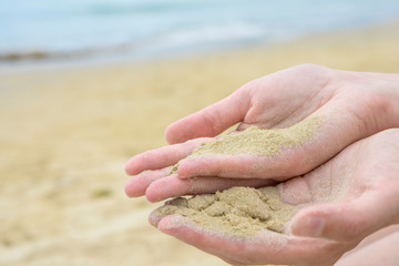 Close up sand in hand. Sand in female hand at beach.