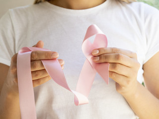Close-up woman holding pink awareness ribbon