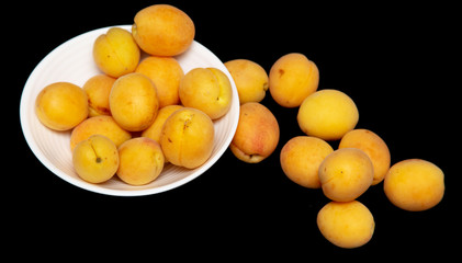 Ripe apricot in a white plate on a black background