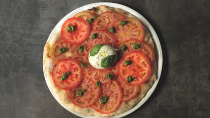 Pizza with tomatoes, pesto and mozzarella on a dark background 