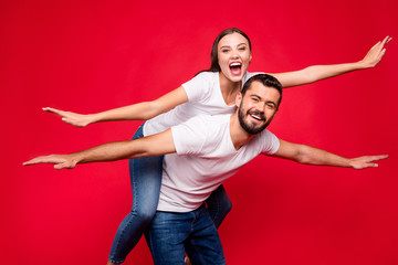 Photo of charming trendy casual cute nice beautiful couple of two people wearing jeans denim white t-shirt piggyback to be flying away abroad while isolated with red background
