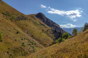 Trans-Ili Alatau mountain range of the Tien Shan system in Kazakhstan near the city of Almaty. Rocky peaks covered with snow and glaciers in the middle of summer under clouds