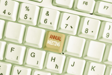 Writing note showing Annual Meeting. Business concept for yearly meeting of the general membership of an organization White pc keyboard with note paper above the white background