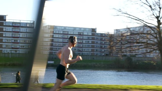Fitness man on run, muscly bodybuilder running with his shirt off 