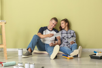 Happy young couple choosing color of walls in their new house