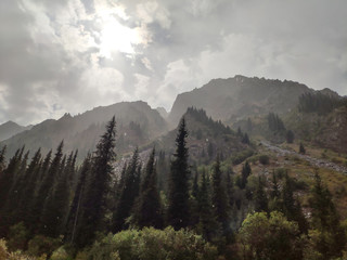 Trans-Ili Alatau mountain range of the Tien Shan system in Kazakhstan near the city of Almaty. Rocky peaks covered with snow and glaciers in the middle of summer under clouds