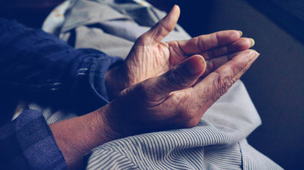 Praying hands of  Old  woman  on a  desk background.