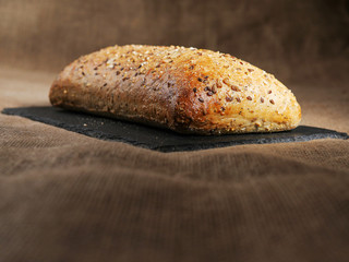 Fresh sourdough bread with nuts on a slate plate and hessian surface.