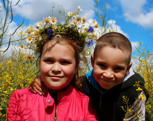 A boy and a girl play in a flower meadow in the spring. 