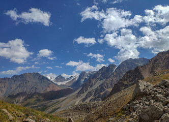 Trans-Ili Alatau mountain range of the Tien Shan system in Kazakhstan near the city of Almaty. Rocky peaks covered with snow and glaciers in the middle of summer under clouds