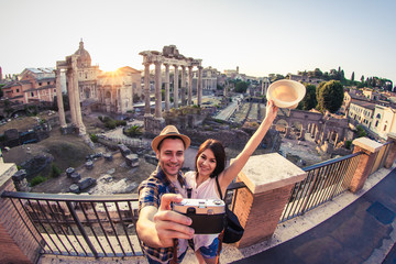 Young couple tourist looking at Roman Forum at sunrise and kissing taking selfie. Historical...