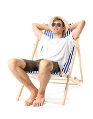 Young man relaxing on sun lounger against white background