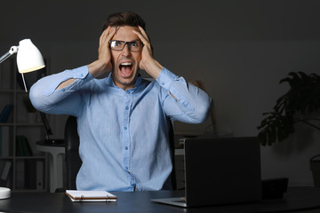 Stressed young man at workplace late in evening