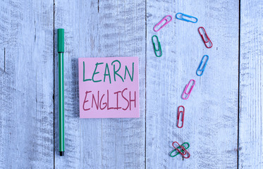 Word writing text Learn English. Business photo showcasing Universal Language Easy Communication and Understand Pastel colour note paper placed next to stationary above the wooden table