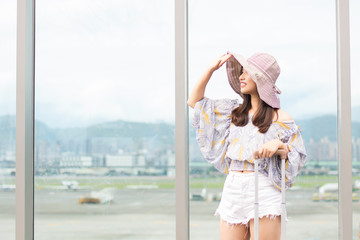 Young asian woman is holding luggage and looking forward to the trip at airport.