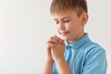 Praying little boy on light background