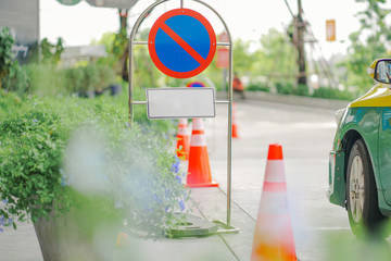 no parking sign with some car  nearby and blurred green foreground
