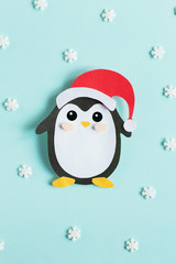 Christmas penguin from paper on a blue background with snowflakes © Elena