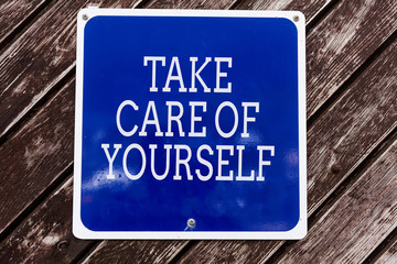 Obraz premium Handwriting text writing Take Care Of Yourself. Conceptual photo a polite way of ending a gettogether or conversation Empty blue board with copy space above wooden background