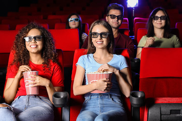 Friends with popcorn watching movie in cinema