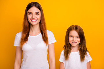 Portrait of charming ladies looking at camera with beaming smile isolated over yellow background