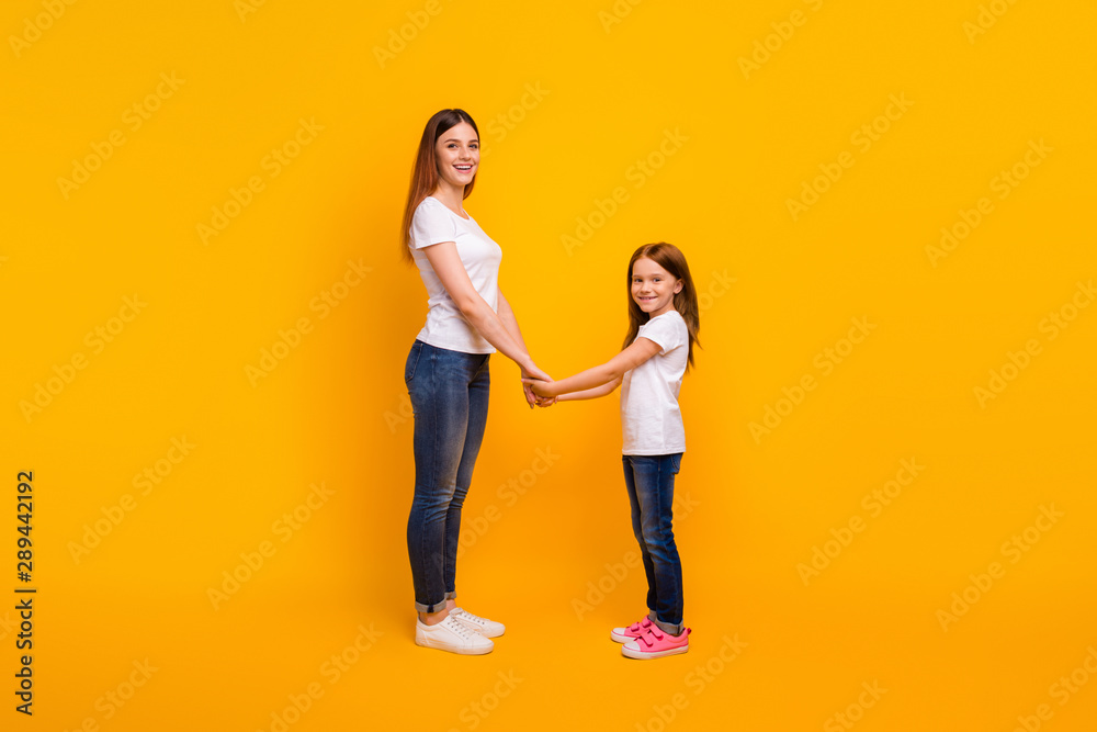 Poster full body profile side photo of cheerful mom with her child holding hands smiling isolated over yell