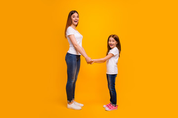 Full size profile side photo of impressed mom holding her child having long foxy hairstyle screaming wearing white t-shirt isolated over yellow background