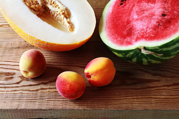 red sweet watermelon. fragrant melon. three ripe peaches. on a wooden table 