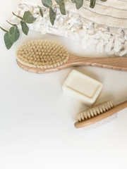 Body brush with wooden handle, pumice, white towel and a piece of soap on a white background. Top view.