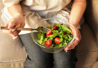Woman eating tasty salad at home, closeup