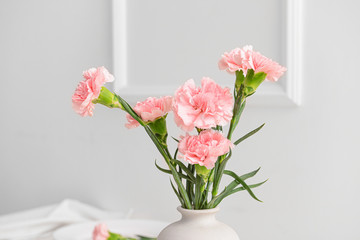 Beautiful carnation flowers in vase on light background