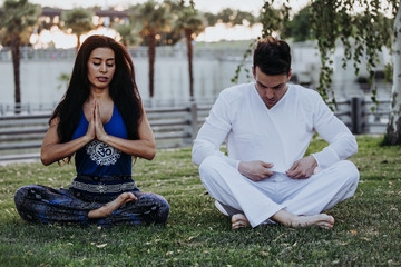 Caucasian man and Latin woman meditate in a park in Madrid. Concentration and relaxation in couple