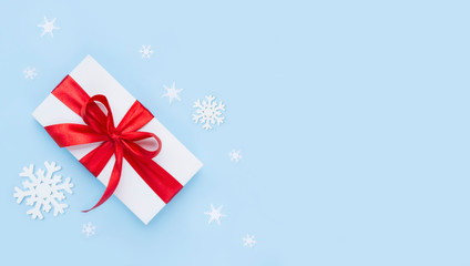 White gift box with red ribbon on blue frosty background