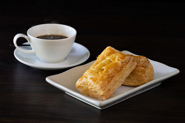 Chicken Pie sprinkle with dry pumpkin seed in white dish and black coffee in cup, all on dark wooden background