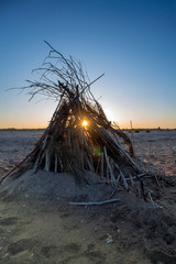 The rays of the setting sun through a straw hut on the shore. Durankulak, Northern Black Sea Coast, Bulgaria.