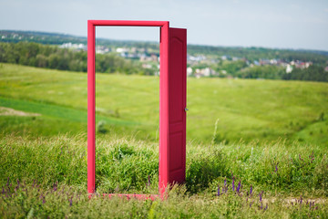 Fototapeta na wymiar red, open door in the field