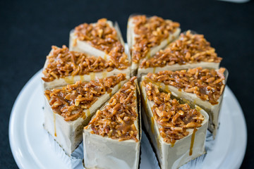 piece of Coffee almond caramel cake on white plate in coffee shop on black background