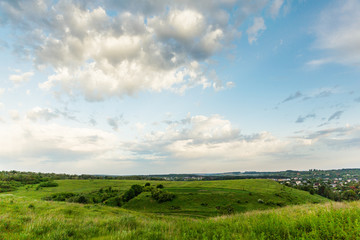 landscape of fields with hills against the textured sky at sunrise