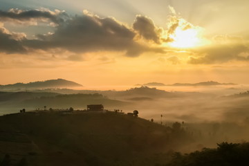 Mountain view morning of top hills and forest around with sea of fog with yellow sun light in the sky background, sunrise at Wat Kong Niam View Point, Khao Kho, Phetchabun, Thailand.