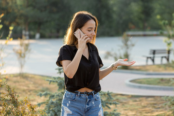 A young girl sits on a bench in a park and makes notes. Dressed in a free style. Business woman talking on the phone with customers.	