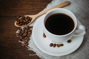 Coffee cup and roasted coffee beans on the old wooden floor.