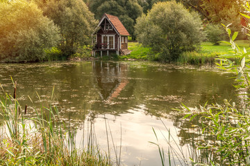 Fototapeta premium Wooden cabin near the edge of a small lake