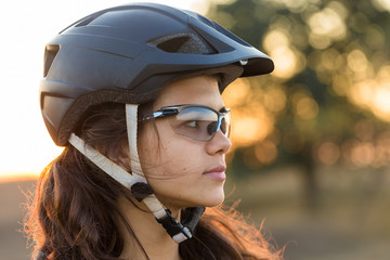 Girl on a mountain bike on offroad, beautiful portrait of a cyclist at sunset, Fitness girl rides a modern carbon fiber mountain bike in sportswear, a helmet, glasses and gloves.	