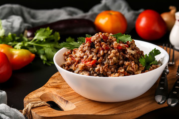 Healthy buckwheat cooked with vegetables in a white bowl on a dark background, a dish of Azerbaijani cuisine, horizontal orientation