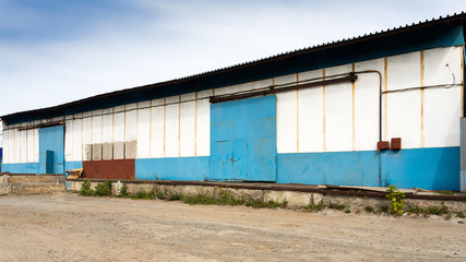 Fototapeta na wymiar Facade on large industrial building made of metal white and blue panels. Industrial concept of transportation, loading and storage of goods