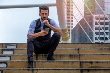 businessman sitting on stairs and using mobile phone