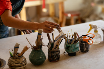Female potter in a pottery studio choosing tools