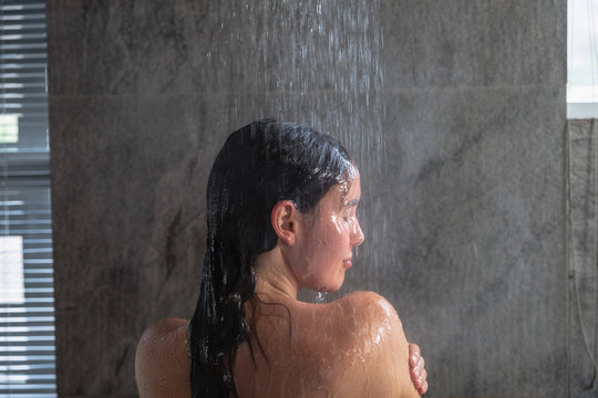 Young brunette woman taking a shower in a modern bathroom